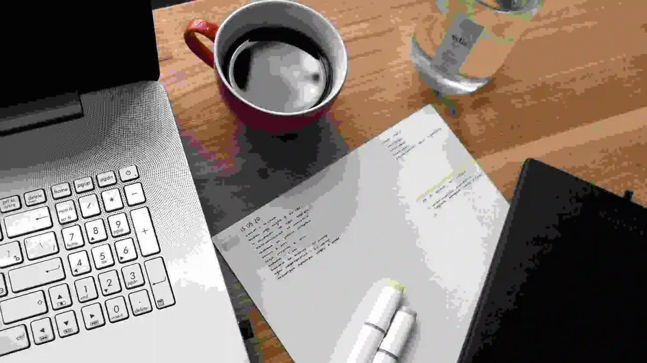 Open laptop, coffee cup, and handwritten study notes on a wooden desk.